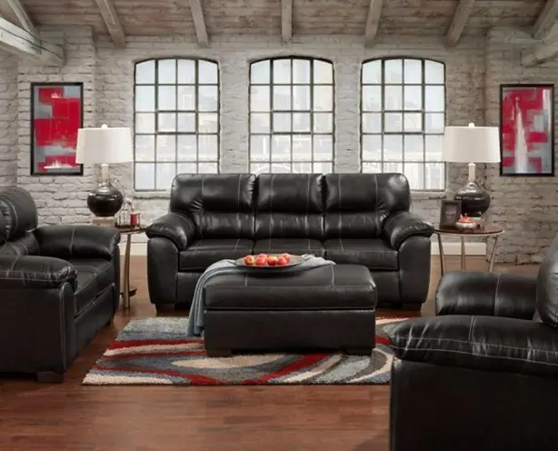Black bonded leather sofa, loveseat and chair with red abstract artwork in a brick loft