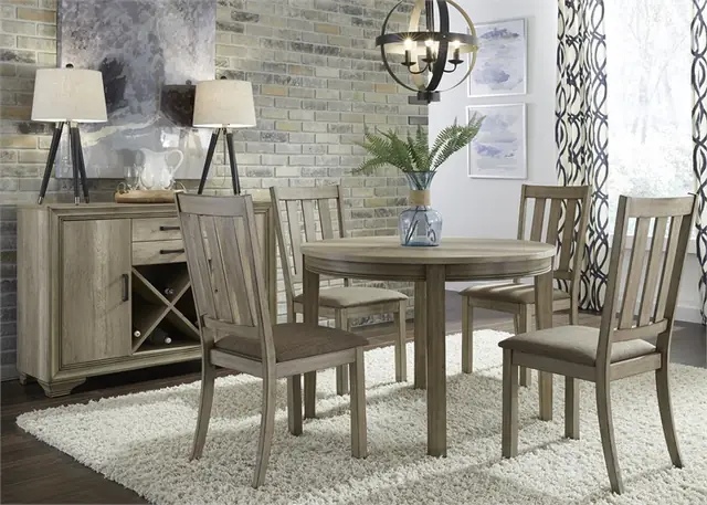 Driftwood grey round dining table with slat-back chairs and a sideboard